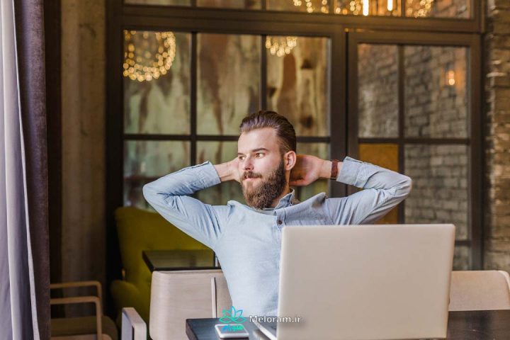 پسری با ریش های بلند که پشت میز کار خود نمی تواند آرام باشد.