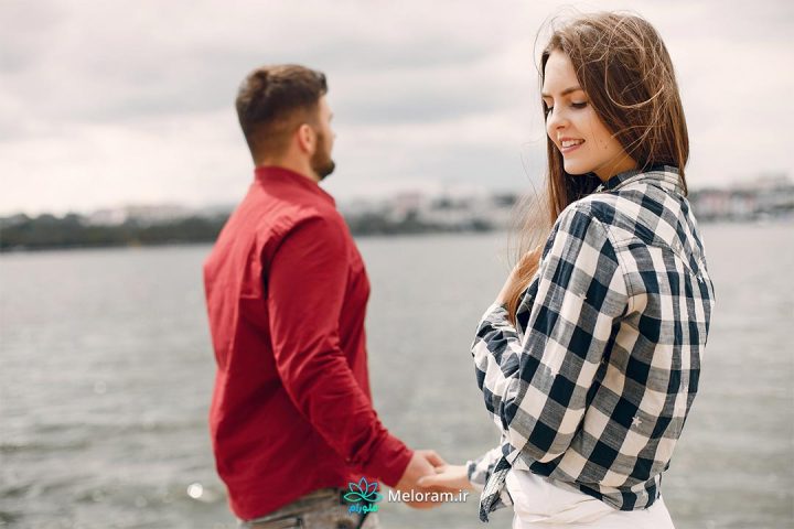 دختری کنار آب در حال لبخند زدن بخاطر شروع رابطه جدید.
