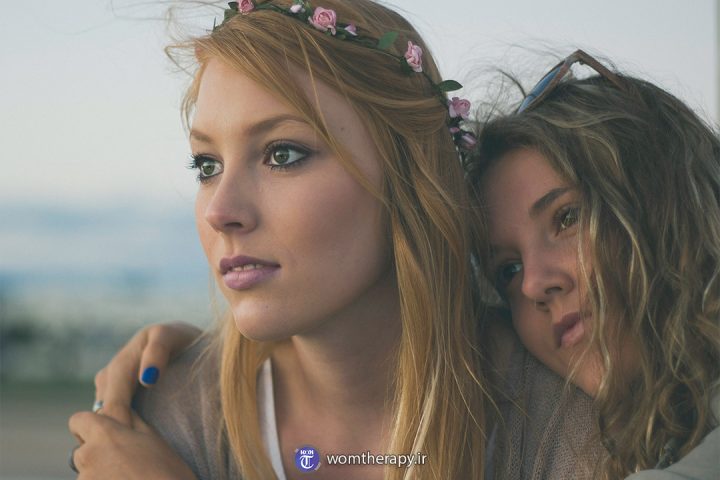 دو دوست دختر که در آغوش هم به دور دست ها نگاه می کنند.