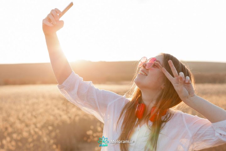 دختری با پیراهن سفید در حال سلفی گرفتن