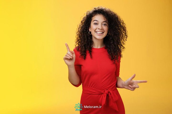 زنی شاد با موهای فر و لباس قرمز در پس زمینه زرد